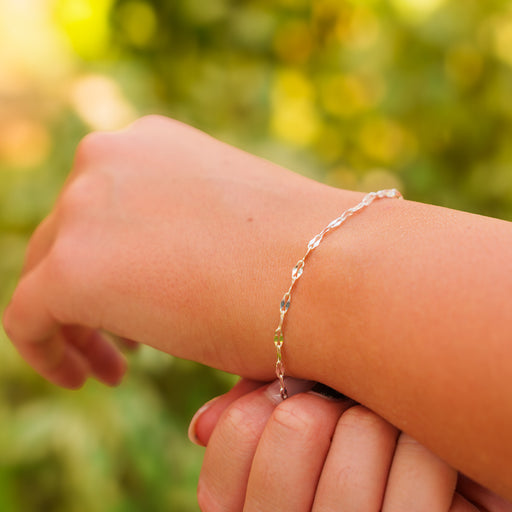A lifestyle photo highlighting a hammered silver permanent jewelry chain worn as a delicate wrist bracelet.