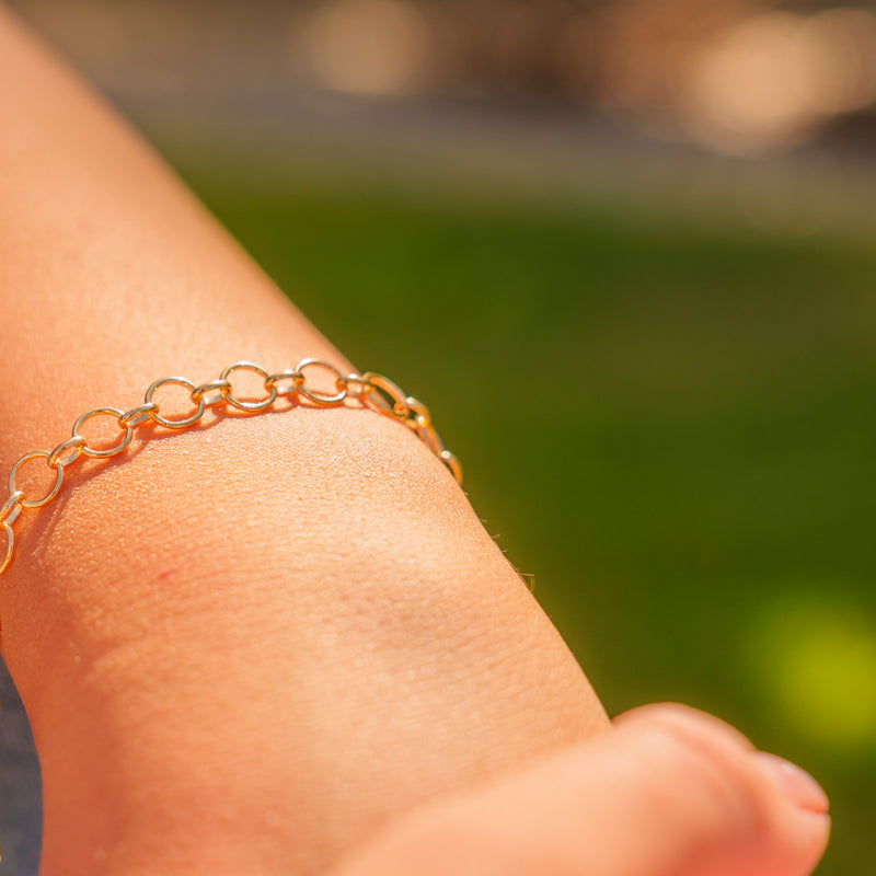 A warm lifestyle photo showcasing a gold interlocking thick round link permanent jewelry chain on a wrist.
